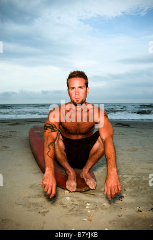 Surfer at beach sitting on surfboard, portrait