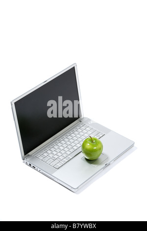 A green apple sitting on a laptop isolated Stock Photo