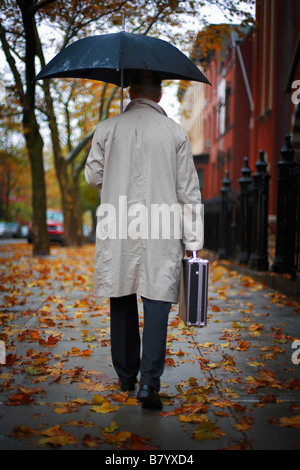 Man walking on the street under umbrella Stock Photo