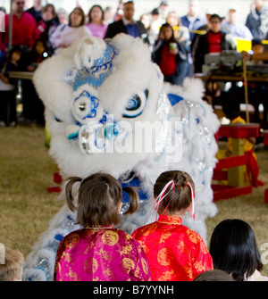 Young girls in Chinese costumes observing a southern style Chinese Lion Dance Stock Photo