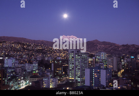 Full moon rising over Mt Illimani and high rise buildings in central La Paz, Bolivia Stock Photo