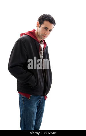 Cool handsome mischievous male wearing a red hoodie black coat and jeans with hands in pocket and head down isolated Stock Photo