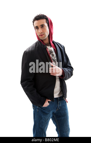 Cool handsome male wearing a red hoodie black coat and jeans with hands in pocket isolated Stock Photo