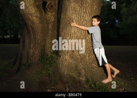Tree Hugger Concept of a Young Boy Hugging Tree with his Legs and