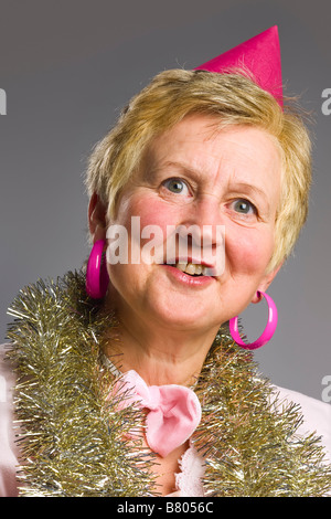 Portrait of middle aged woman wearing pink party hat and tinsel Stock Photo