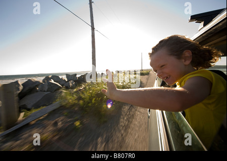 A young boy sticks his head out of the window during a drive. Stock Photo