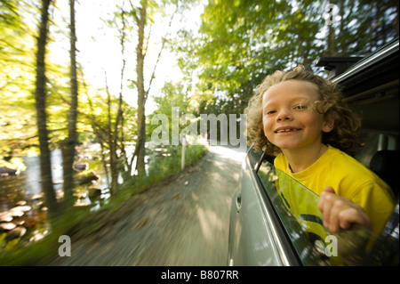 A young boy sticks his head out of the window during a drive. Stock Photo