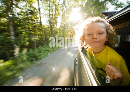 A young boy sticks his head out of the window during a drive. Stock Photo