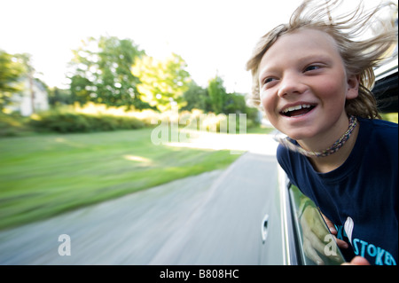 A young boy sticks his head out of the window during a drive. Stock Photo