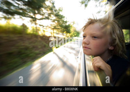 A young boy sticks his head out of the window during a drive. Stock Photo