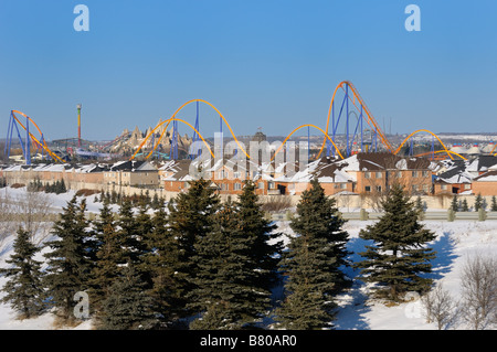Closed amusement park Wonderland roller coaster and evergreen trees in winter next to a residential housing development near Toronto Stock Photo