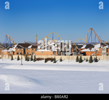 Closed amusement park Wonderland roller coaster with field of snow in winter next to a residential housing development near Toronto Stock Photo
