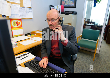 Male office manager working at desk on the phone and computer Toronto Canada Stock Photo