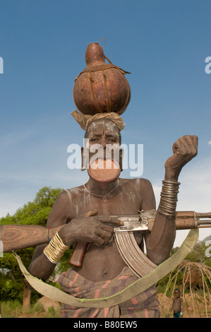 Mursi women with plate in her lips showing her Kalashnikov Mago National Park Omovalley Ethiopia Africa Stock Photo