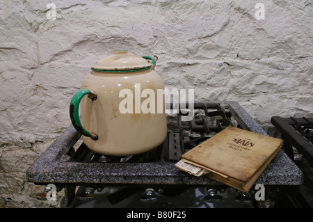 Main cast iron gas cooker from c1900-1920 with enamelled kettle and cookery book on hob Stock Photo