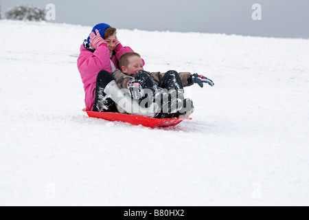 Woman and child sledging in deep snow Cleeve Hill Cotswolds UK Stock Photo