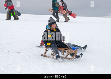 Child sledging in deep snow Cleeve Hill Cotswolds UK Stock Photo