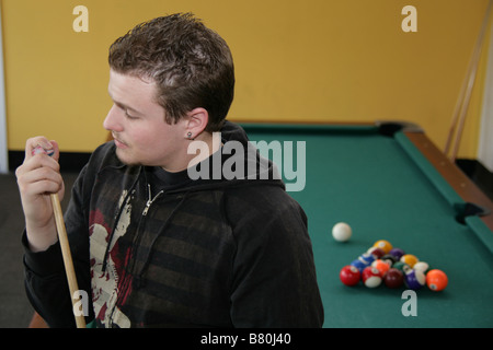Young man chalking his pool stick. Stock Photo
