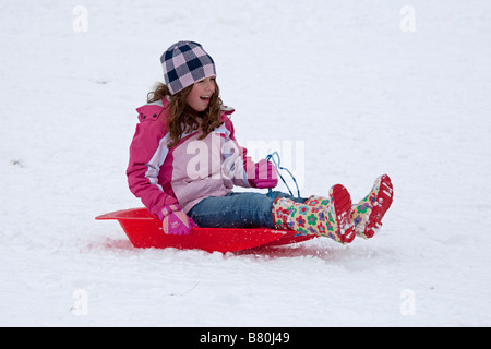 Girl sledging in deep snow Cleeve Hill Cotswolds UK Stock Photo