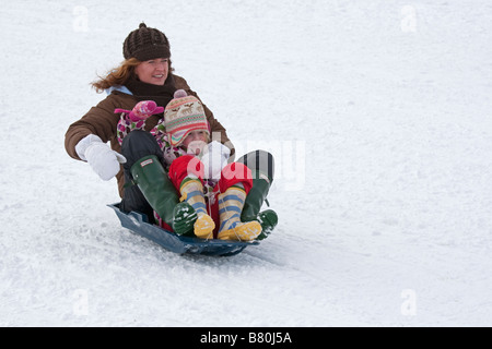Mother and daughter sledging in deep snow Cleeve Hill Cotswolds UK Stock Photo