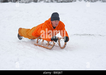 Man sledging in deep snow Cleeve Hill Cotswolds UK Stock Photo
