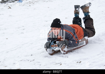 Man sledging in deep snow Cleeve Hill Cotswolds UK Stock Photo