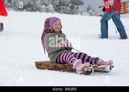 Girl sledging in deep snow Cleeve Hill Cotswolds UK Stock Photo