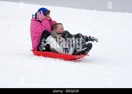 Woman and child sledging in deep snow Cleeve Hill Cotswolds UK Stock Photo