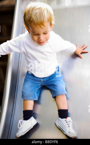 little boy at playground sliding down slide Stock Photo