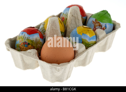 single free range egg placed in a box of small wrapped chocolate easter eggs Stock Photo