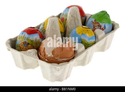 single free range broken eggshells placed in a box of small wrapped chocolate easter eggs Stock Photo