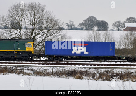 APL shipping container on freightliner train in snow, UK