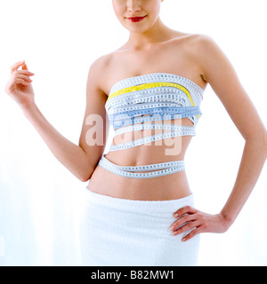 Young woman wrapped from chest to waist with measuring tape mid section Stock Photo