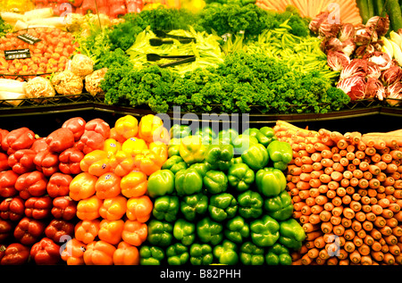 A produce bin in a supermarket displays peppers parsley sweet peas carrots and endive Stock Photo
