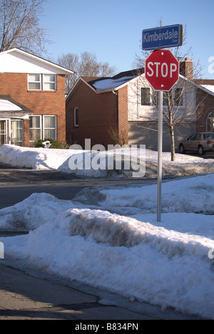 Dirty melting Snow on the side street/Road with Stop sign and Houses at the back in Scarborough Toronto Stock Photo
