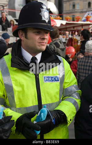 Metropolitan Police Officer in London holding a toy of the 2010 Shanghai mascot Haibao in Trafalgar Square Stock Photo