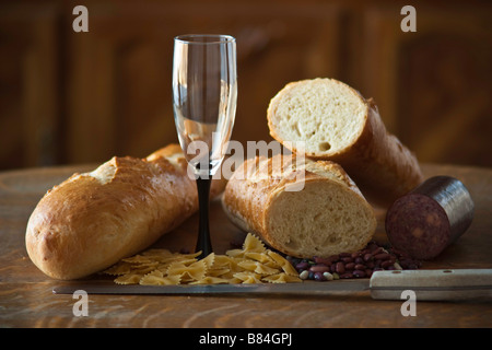 Fresh bread and wine glass, pasta, beans, salami Stock Photo