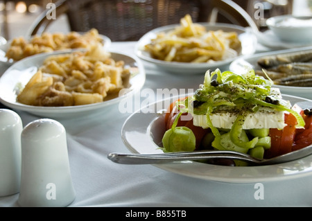 Traditional Greek salad with feta cheese on white plate and table cloth, closeup view, healthy Mediterranean diet, meze Stock Photo