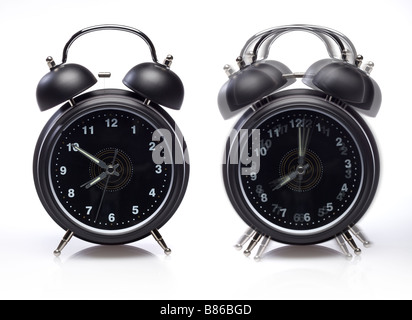 Two retro alarm clocks one still one ringing on white with motion blur Stock Photo