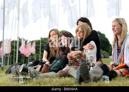 A group of girls enjoy the music sat among flags at the Glastonbury Festival in Pilton, Somerset in the UK. Stock Photo