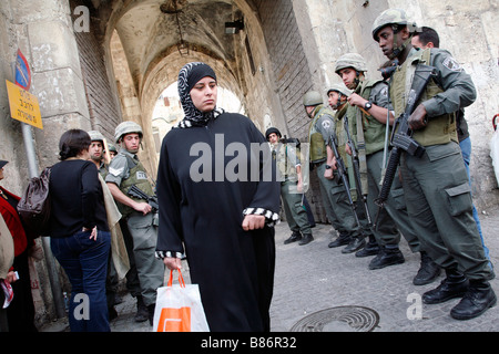 A Palestinian woman walking past Israeli police guarding an entrance into the Old City of Jerusalem. Stock Photo