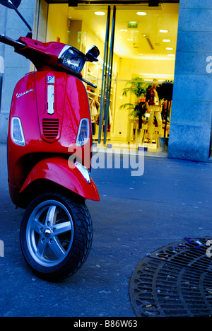 Paris France, Shopping Red Painted Vespa Motor scooter parked on Sidewalk Outside at Dusk Stock Photo