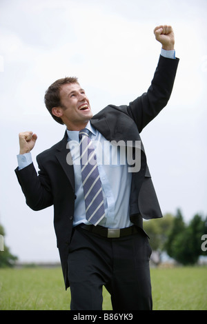 Businessman smiling and raising his fist in the air, with office ...