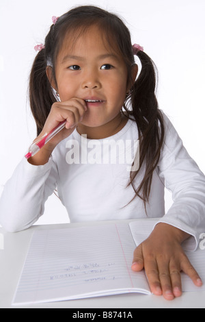 Little girl is thinking about her writing Stock Photo