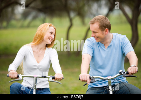 Couple riding bicycles looking at each other Stock Photo