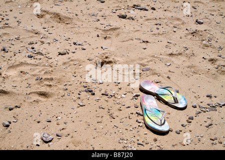 Rainbow coloured flipflops on a pebbly sand beach Stock Photo