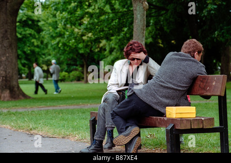 Woman sat on bench reading book in Victoria Park an urban public park opened in 1897 covering 20 acres Cardiff South Wales UK Stock Photo