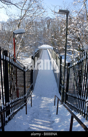 Steps leading to footbridge over railway line, all covered in snow Stock Photo