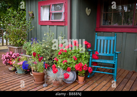 Vashon Island, WA: Colorful deck with potted flowers and blue rocker in the village of Ellisport Stock Photo