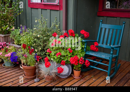 Vashon Island, WA: Colorful deck with potted flowers and blue rocker in the village of Ellisport Stock Photo